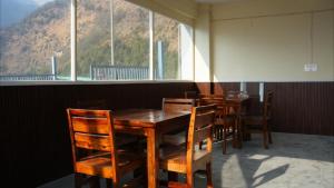 a dining room with tables and chairs and a large window at Mandola Stays in Girgaon