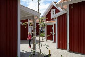 a little girl walking through a row of red buildings at Apelvikens Camping & Cottages in Varberg +17 photos