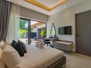 a bedroom with a bed and a desk and a television at Dara Villas - Rawai in Rawai Beach
