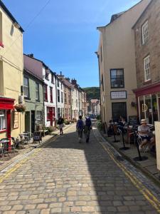 a cobblestone street with people walking down the street at Kurnell Cottage, Staithes in Staithes