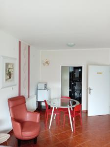 a dining room with a glass table and red chairs at Apartments Košević in Osijek