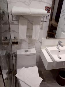 a bathroom with a toilet and a sink and towels at โรงแรมสวนดุสิต เพลส in Ban Nong Chaeng