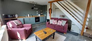 a living room with two chairs and a table at Whitewells Farm Cottages - 7 exceptionally well appointed pet friendly barn conversions set in 10 acres of gardens, fields and woodland suitable from 2 to 24 people with breathtaking views towards the Malvern Hills, Herefordshire and Worcestershire in Mathon