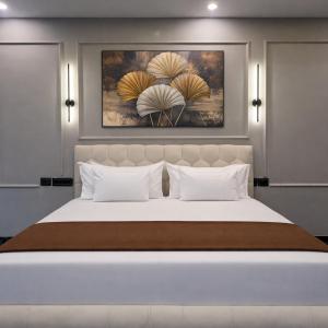 a bedroom with a large white bed with two paintings on the wall at The Boutique Studio Near Green Park Delhi- By ACESTAYZ in New Delhi