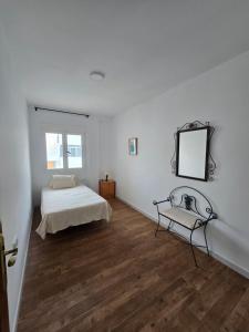 a bedroom with a bed and a mirror and a chair at La Artesana Níjar in Níjar