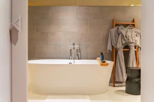a bath tub in a bathroom with a robe at Cross Chiang Mai Riverside in Chiang Mai