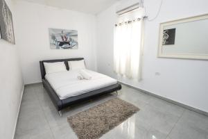 a bed in a white room with a rug at אגם בגליל -וילה ו-3 סוויטות מקסימות למשפחות עם בריכה מחוממת in Wadi Keren