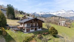 a house on a hill with mountains in the background at Chalet Sapi in Combloux