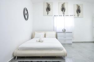 a white bedroom with a bed and a clock on the wall at אגם בגליל -וילה ו-3 סוויטות מקסימות למשפחות עם בריכה מחוממת in Wadi Keren