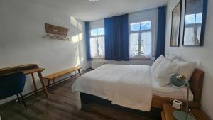 a bedroom with a bed and a desk and two windows at The Aarburg Hotel & Café in Interlaken