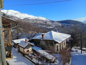 a house covered in snow with mountains in the background at La dimora del castagno in Ormea