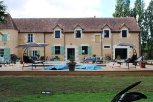 a building with chairs and umbrellas in front of it at Le Chêne Guesthouse in Aunou-sur-Orne