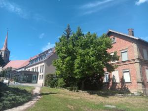 a tree in front of a brick building with a church at Ferienhaus by Rossano Boutique Hotel & Ristorante in Ansbach