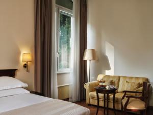 a hotel room with a bed and a chair and a window at Amadria Park Hotel Agava in Opatija