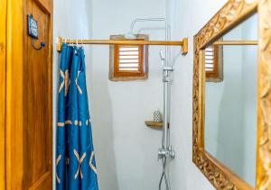 a shower with a blue shower curtain and a mirror at Dhow House - Rooftop Lounge with Sunrise Views in Bagamoyo +41 photos