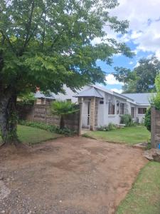 a white house with a fence and a tree at 33 On Loop, Flat 2 in Ladybrand