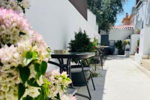 a patio with tables and chairs and pink flowers at Larnaca - Studio - Sleeps 4 - Garden - Parking in Larnaca