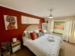 a bedroom with a large bed with red walls at Serenity in Fish Hoek