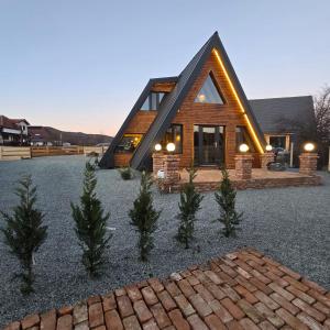ein Blockhaus mit einer Gartengestaltung mit Bäumen davor in der Unterkunft FreeDom Chalet in Verneşti + 9 Fotos