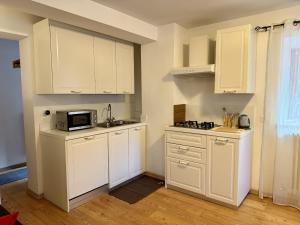 a kitchen with white cabinets and a microwave at Il Molino nel bosco - PT in Alleghe