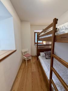a bedroom with two bunk beds and a chair at Il Molino nel bosco - PT in Alleghe