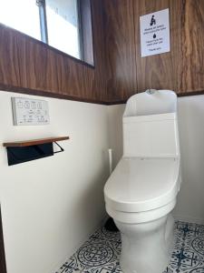 a white toilet in a bathroom with a window at KAMIKURA stay in Shingū