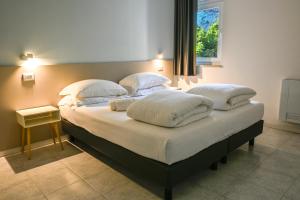 a bedroom with a bed with white sheets and pillows at Appartamenti Villa al Fiume in Nago-Torbole