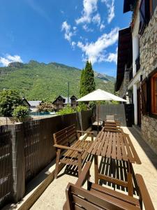 two wooden benches and an umbrella on a patio at Inmocyma La terraceta de Linsoles-Valle de Benasque in Benasque