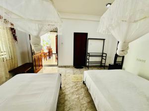 two beds in a bedroom with white curtains at Sigiri Rainbow Lodge in Sigiriya