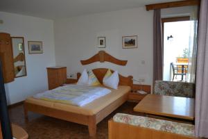 a bedroom with a bed with a wooden headboard and a table at Kastnerhof in Meltina
