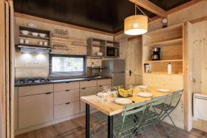 a kitchen with a wooden table and chairs at Huttopia Divonne les Bains in Divonne-les-Bains