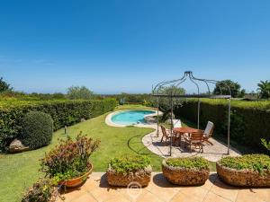 a garden with a table and chairs and a swimming pool at Estay - Carrubo Oasis - Swimming pool & Garden in Pula +39 photos