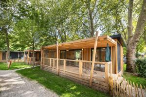 a cabin in the woods with a fence at Huttopia Divonne les Bains in Divonne-les-Bains