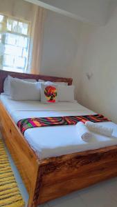 a wooden bed in a room with a window at Charming chalet Diani in Diani Beach