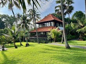 a house with palm trees in front of a yard at The Palms - Seraya Shores Retreat Bali in Seraya