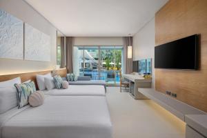 a hotel room with two beds and a flat screen tv at The Kee Resort & Spa in Patong Beach