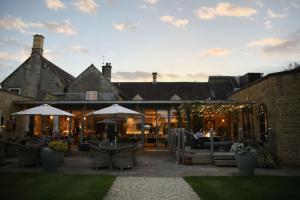 a patio with chairs and umbrellas in front of a building at Dormy House Hotel in Broadway