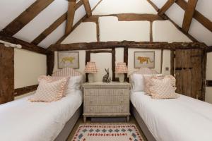 two twin beds in a room with wooden beams at The Nook by The Butler Collection in Petworth