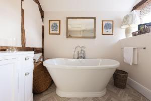 a bathroom with a white tub and a mirror at The Nook by The Butler Collection in Petworth