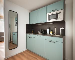 a kitchen with blue cabinets and a mirror at Limehome Mannheim City Center in Mannheim
