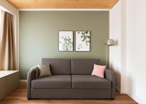 a living room with a gray couch with pink pillows at Limehome Mannheim City Center in Mannheim