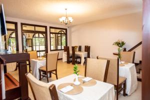 a restaurant with tables and chairs and a piano at Cozy Stead Hotel - Haven House, Gigiri in Nairobi