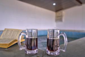 two glass mugs sitting on a table with a book at Hotel Padma in Morjim