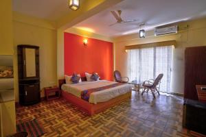a bedroom with a bed and a red wall at Hotel Padma in Morjim