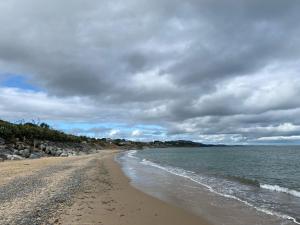 a beach with rocks and the ocean on a cloudy day at Namah Stay in Courtown