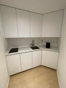 an empty kitchen with white cabinets and a sink at Wasserfall - Zentrum - Balkon - Seeblick - Küche in St. Moritz