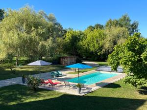 a swimming pool with two umbrellas and two chairs at La Tour de la Conterie in Beaumont-Village
