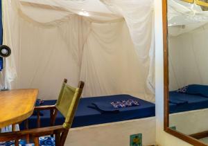 a room with a bed and a table and a mirror at Gecko Cottage - Cosy 2-Bedroom in Bagamoyo Old Town in Bagamoyo