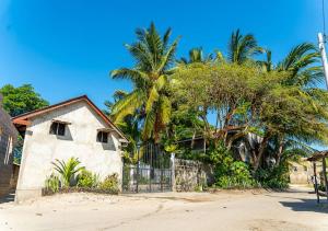 a house on the beach with palm trees at Gecko Cottage - Cosy 2-Bedroom in Bagamoyo Old Town in Bagamoyo