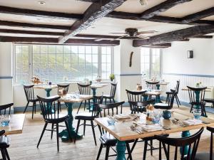 a restaurant with wooden tables and chairs and large windows at Lugger Hotel ‘A Bespoke Hotel’ in Portloe
